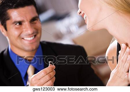 Mid adult man giving an engagement ring to a young woman View Large Photo Image Stock Image - Mid adult man giving an engagement ring to a young woman. Fotosearch