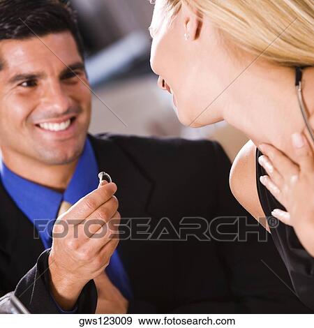 Stock Photo - Mid adult man giving an engagement ring to a young woman. Fotosearch