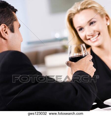 Mid adult man holding a glass of red wine with a young woman sitting beside him View Large Photo Image Stock Image - Mid adult man holding a glass of red wine with a young woman sitting beside him. Fotosearch