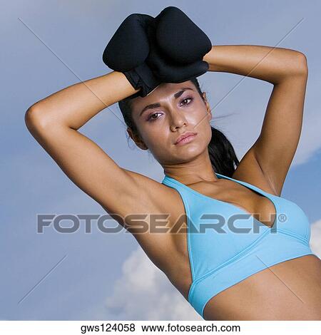 Low angle view of a young woman wearing boxing gloves View Large Photo Image Stock Photo - Low angle view of a young woman wearing boxing gloves. Fotosearch