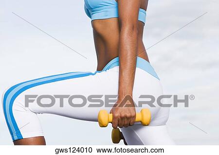Mid section view of a young woman exercising with dumbbells View Large Photo Image Stock Image - Mid section view of a young woman exercising with dumbbells. Fotosearch