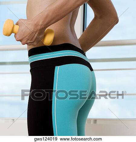Mid section view of a young woman exercising with dumbbells View Large Photo Image Stock Photo - Mid section view of a young woman exercising with dumbbells. Fotosearch