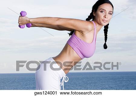 Portrait of a young woman exercising with dumbbells View Large Photo Image Stock Image - Portrait of a young woman exercising with dumbbells. Fotosearch