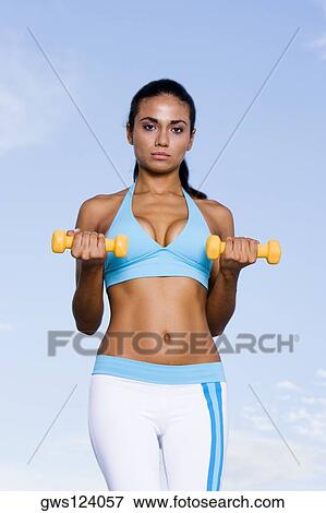 Portrait of a young woman exercising with dumbbells View Large Photo Image Stock Photo - Portrait of a young woman exercising with dumbbells. Fotosearch