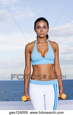 Portrait of a young woman holding dumbbells View Large Photo Image Stock Photo - Portrait of a young woman holding dumbbells. Fotosearch