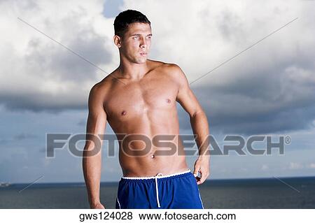 Young man standing bare chested View Large Photo Image Stock Photo - Young man standing bare chested. Fotosearch