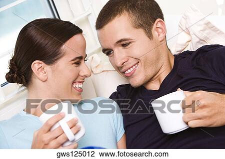 Close-up of a young couple holding coffee cups looking at each other View Large Photo Image Stock Image - Close-up of a young couple holding coffee cups looking at each other. Fotosearch