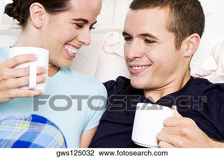 Stock Image - Close-up of a young couple holding coffee cups. Fotosearch