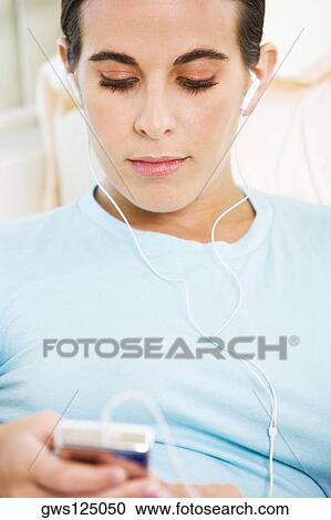 Close-up of a young woman listening to an MP3 player View Large Photo Image Stock Image - Close-up of a young woman listening to an MP3 player. Fotosearch