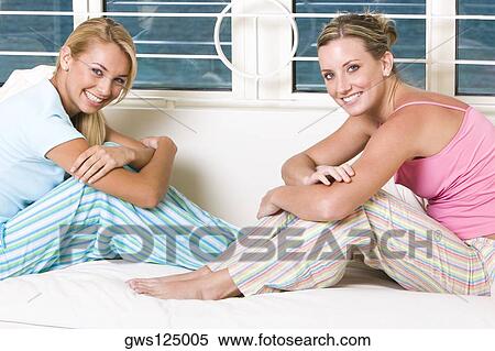 Stock Photography - Portrait of two young women sitting on a bed. Fotosearch