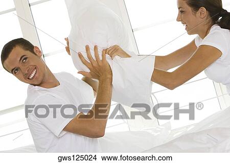 Side profile of a young couple having a pillow fight View Large Photo Image Picture - Side profile of a young couple having a pillow fight. Fotosearch