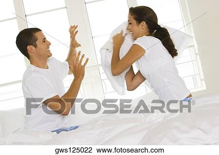 Side profile of a young couple having a pillow fight on the bed View Large Photo Image Stock Image - Side profile of a young couple having a pillow fight on the bed. Fotosearch