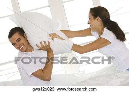 Side profile of a young couple having a pillow fight View Large Photo Image Stock Image - Side profile of a young couple having a pillow fight. Fotosearch