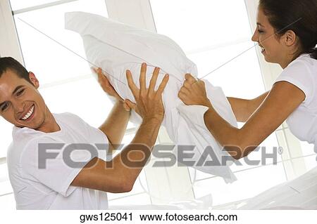 Side profile of a young couple having a pillow fight View Large Photo Image Stock Image - Side profile of a young couple having a pillow fight. Fotosearch
