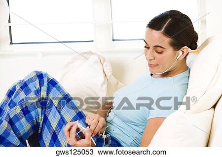 Side profile of a young woman listening to an MP3 player View Large Photo Image Stock Image - Side profile of a young woman listening to an MP3 player. Fotosearch