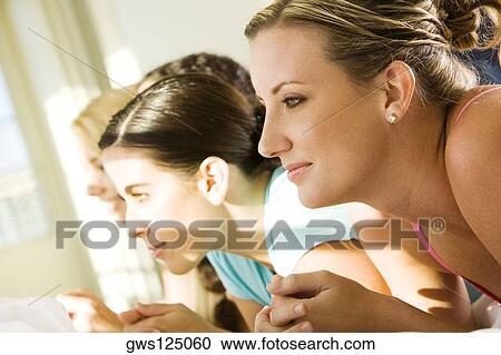 Stock Image - Side profile of four young women lying side by side. Fotosearch