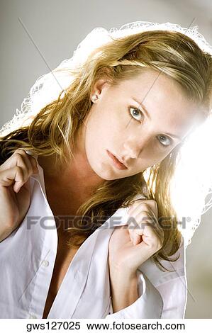 Stock Photography - Portrait of a young woman holding her shirt collar. Fotosearch