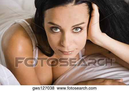 Portrait of a young woman lying down on a bed View Large Photo Image Stock Photo - Portrait of a young woman lying down on a bed. Fotosearch