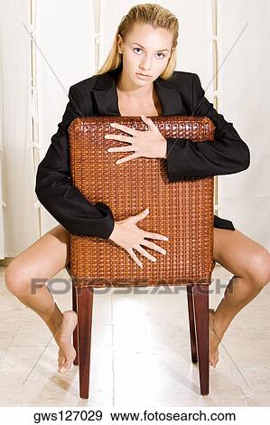 Stock Photo - Portrait of a young woman sitting on a chair. Fotosearch