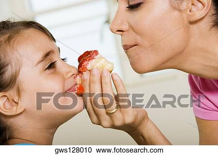 Close-up of mother sharing a pastry with her daughter View Large Photo Image Stock Image - Close-up of mother sharing a pastry with her daughter. Fotosearch