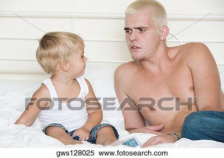 Father and his son sitting on a bed View Large Photo Image Stock Photography - Father and his son sitting on a bed. Fotosearch