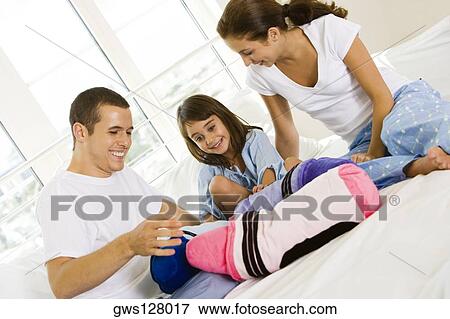 Parents and their daughter sitting on the bed View Large Photo Image Stock Photo - Parents and their daughter sitting on the bed. Fotosearch