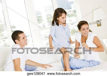 Parents and their daughter sitting on the bed View Large Photo Image Stock Photo - Parents and their daughter sitting on the bed. Fotosearch
