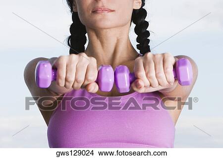 Close-up of a young woman holding dumbbells View Large Photo Image Picture - Close-up of a young woman holding dumbbells. Fotosearch