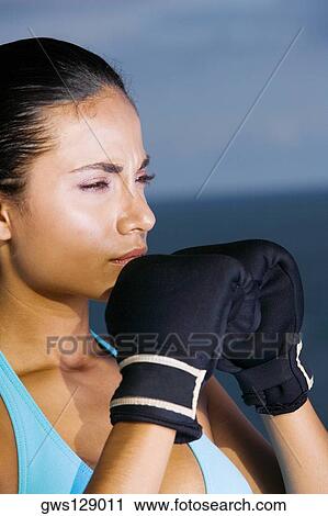 Stock Image - Close-up of a young woman wearing boxing gloves. Fotosearch