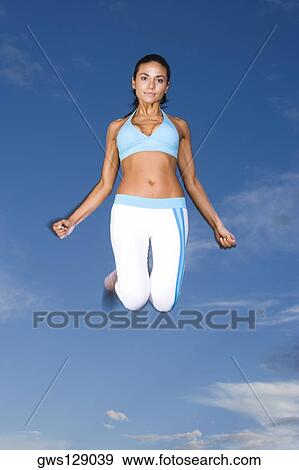 Low angle view of a young woman jumping View Large Photo Image Stock Photo - Low angle view of a young woman jumping. Fotosearch