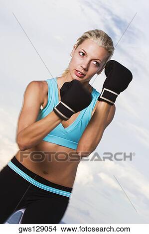 Low angle view of a young woman wearing boxing gloves View Large Photo Image Picture - Low angle view of a young woman wearing boxing gloves. Fotosearch