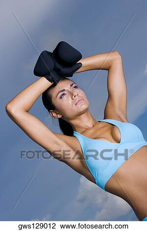 Stock Image - Low angle view of a young woman wearing boxing gloves. Fotosearch