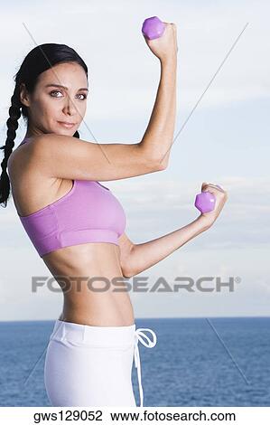 Portrait of a young woman exercising with dumbbells View Large Photo Image Stock Image - Portrait of a young woman exercising with dumbbells. Fotosearch