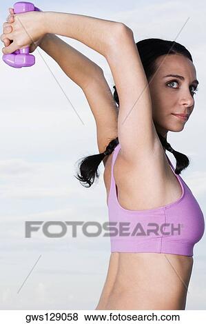 Portrait of a young woman exercising with dumbbells View Large Photo Image Stock Photo - Portrait of a young woman exercising with dumbbells. Fotosearch