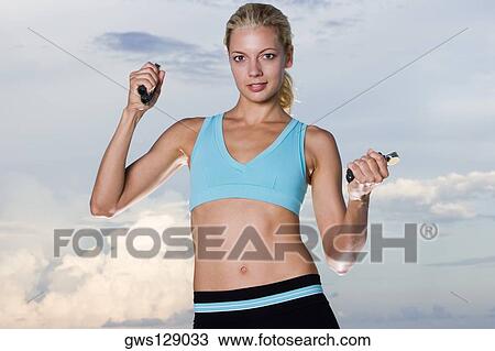 Stock Image - Portrait of a young woman squeezing hand grips. Fotosearch