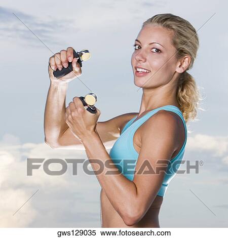 Stock Photography - Portrait of a young woman squeezing hand grips. Fotosearch