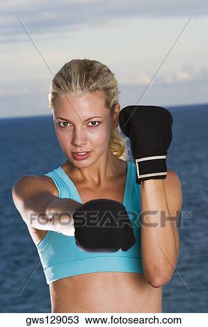 Stock Image - Portrait of a young woman wearing boxing gloves. Fotosearch