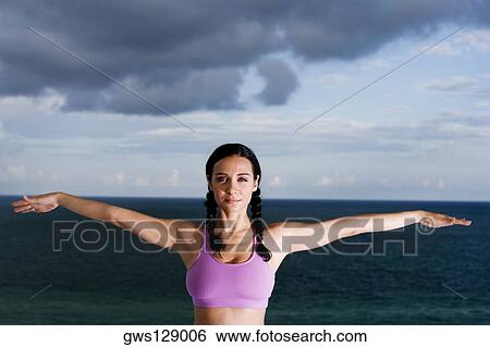 Stock Photograph - Portrait of a young woman with her arms outstretched. Fotosearch