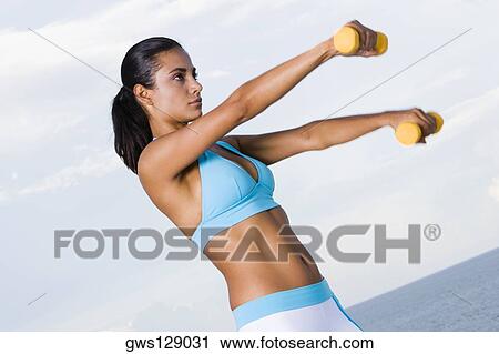 Side profile of a young woman exercising with dumbbells View Large Photo Image Stock Image - Side profile of a young woman exercising with dumbbells. Fotosearch