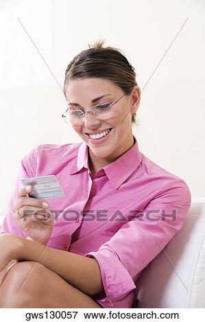 Close-up of a young woman looking at a credit card View Large Photo Image Stock Photo - Close-up of a young woman looking at a credit card. Fotosearch
