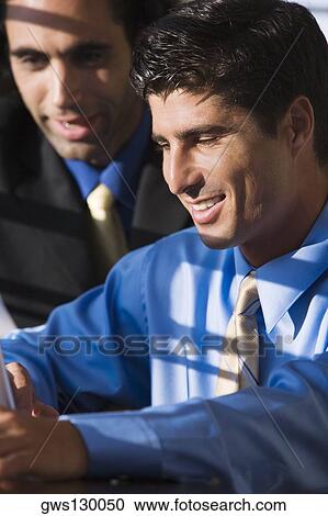 Stock Image - Close-up of two businessmen using a laptop. Fotosearch
