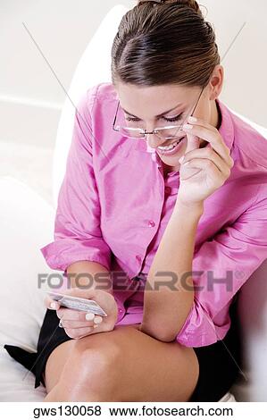 High angle view of a young woman looking at a credit card View Large Photo Image Stock Photo - High angle view of a young woman looking at a credit card. Fotosearch