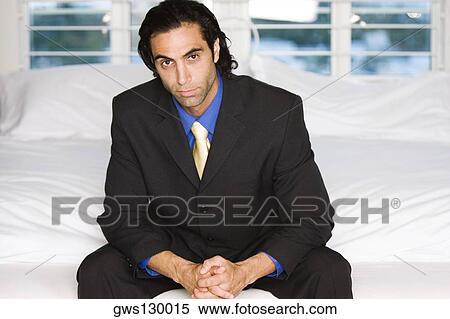 Portrait of a businessman sitting on a bed View Large Photo Image Stock Photography - Portrait of a businessman sitting on a bed. Fotosearch