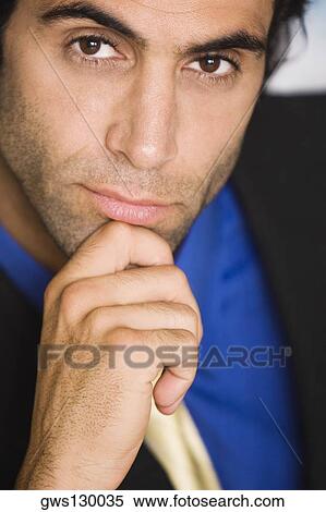 Stock Photography - Portrait of a businessman with his hand on his chin. Fotosearch