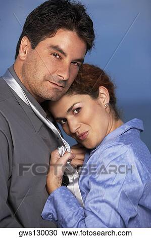 Stock Image - Young woman holding a mid adult man by his tie. Fotosearch
