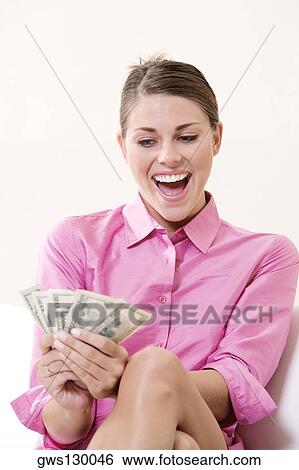 Stock Photograph - Young woman holding US paper currency and laughing. Fotosearch