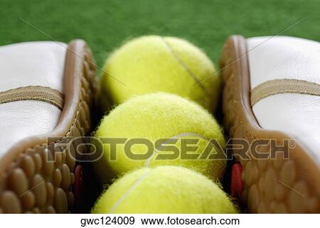 Stock Photo - Close-up of a pair of tennis shoes with three tennis balls. Fotosearch