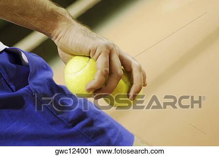 Stock Image - Close-up of a person's hand holding two tennis balls. Fotosearch