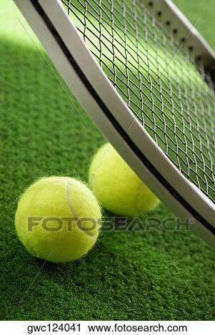 Stock Image - Close-up of two tennis balls with a tennis racket. Fotosearch