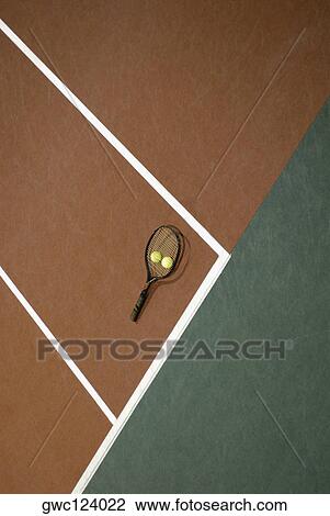 Stock Image - High angle view of two tennis balls and a tennis racket on a tennis court. Fotosearch